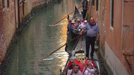 Gondoliers-with-gondolas-in-one-of-many-water-canals-in-Venice-sailing-with-group-of-tourists