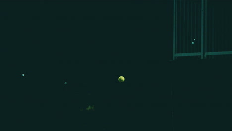 Tennis-ball-floating-at-night-in-extreme-slow-motion-before-being-served-lit-by-stadium-lights,-4k-800fps-tennis-ball-frozen-in-the-air