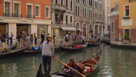 Gondolier-oarsmen-sails-with-gondola-in-water-canal-in-Venice-with-tourists