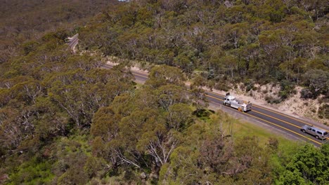 Panning-drone-shot-of-a-truck-passing-on-Alpine-Road-in-Crackenback-area,-Australia