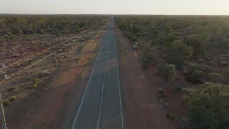 Drohnenclip,-Der-Einen-LKW-Mit-Vier-Waggons-Zeigt,-Der-Auf-Einer-Langen-Geraden-Straße-Durch-Das-Australische-Outback-Fährt