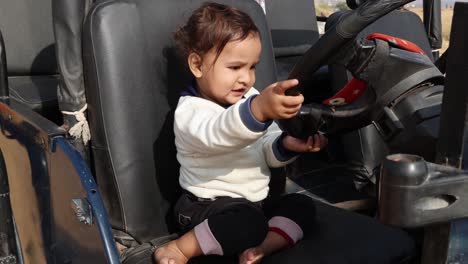 innocent-toddler-cute-expression-while-playing-with-car-handle-at-day-from-flat-angle-video-is-taken-at-rajasthan,-India