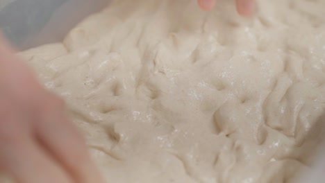 Kneading-dough-with-hands-in-closeup,-top-view