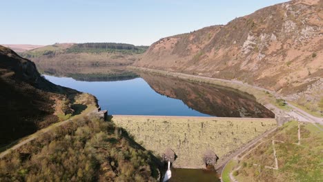 An-aerial-view-of-Caban-Coch-dam-and-reservoir-on-a-sunny-spring-day-in-the-Elan-valley,-Powys,-Wales