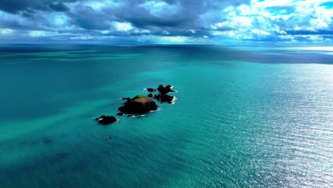 Drone-flying-to-islands-with-emerald-green-sea-and-dramatic-skyline-on-the-Copper-Coast-in-Waterford-Ireland-in-spring-dramatic-establishing-shot