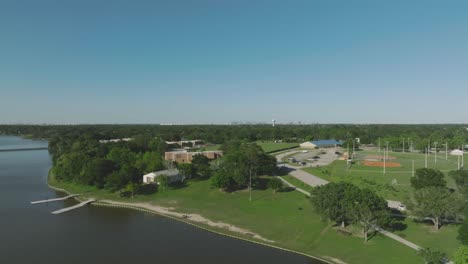 An-aerial-establishing-shot-of-Clear-Lake-Park's-north-side-on-Lake-Kamer-features-boat-docks,-a-kayak-launch,-and-a-fishing-pier,-as-well-as-baseball-and-soccer-fields-in-Pasadena,-Texas