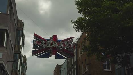 Carnaby-sign-hanging-in-the-air---Union-Jack,-Carnaby-Street,-London,-Day,-low-angle-with-tree