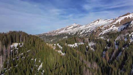 Erstaunliche-Drohne,-Luftaufnahme-Der-Atemberaubenden-Aussicht-Auf-Berge-Und-Schneebedeckte-Bergketten-Auf-Der-Rechten-Seite-Der-Aufnahme-In-Amden-Arvenbüel,-Schweiz,-Bedeckt-Von-Alpinen-Bäumen-Und-Mit-Schnee-übersät
