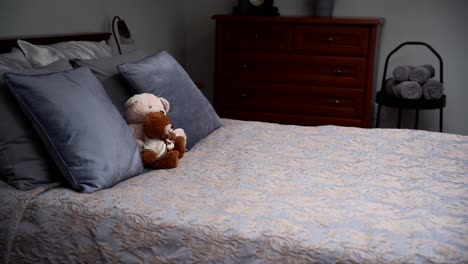 Gemütlich-Eingerichtetes-Schlafzimmer-Mit-Einem-Grauen-Doppelbett-Und-Zwei-Teddybären