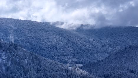 Drohne-Fliegt-Im-Frühling-Langsam-über-Einer-Schneebedeckten-Berglandschaft-Mit-Blauem-Himmel-Und-Großen-Wolken