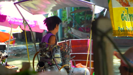 Viejo-Hombre-Local-Tailandés-Navegando-En-Un-Barco-Rústico-En-El-Mercado-Flotante-De-Bangkok