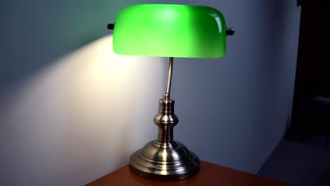 Green-Reading-Lamp-on-a-wooden-desk,-against-the-background-of-a-gray-wall