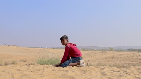 Junge-Spielt-Mit-Gelbem-Sand-In-Der-Wüste-Bei-Tag-Video-Aufgenommen-In-Rajasthan,-Indien