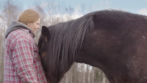 Horse-tenderly-nudges-woman-on-chest-during-equine-therapy-session,-side-view