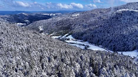 Drone-slow-fly-in-the-Meurthe-valley-in-Plainfaing-with-snow-covered-landscape-during-springtime-with-blue-sky-and-big-clouds