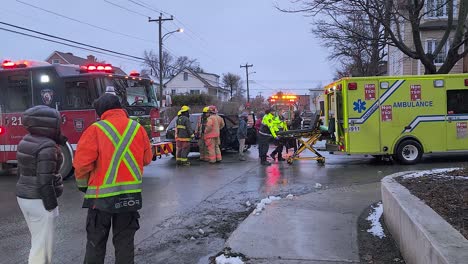 Equipos-De-Emergencia-De-Montreal-Que-Asisten-A-La-Escena-De-Un-Accidente-Automovilístico-Mientras-El-Personal-De-Ambulancia-Carga-Una-Camilla