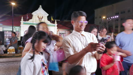 Familias-Tomando-Fotografías-Frente-A-Un-Ayuntamiento-Comunitario-Donde-Se-Lleva-A-Cabo-Un-Evento-En-Bangkok,-Tailandia