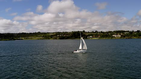 Sailboat-Gliding-on-Lake-Along-the-Coast-on-a-Beautiful-Blue-Sky-Cloudy-Day