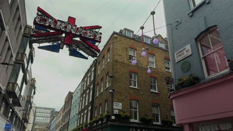 Cartel-De-Carnaby-Colgado-En-El-Aire---Union-Jack,-Carnaby-Street,-Londres,-Día,-ángulo-Bajo-Con-Edificios