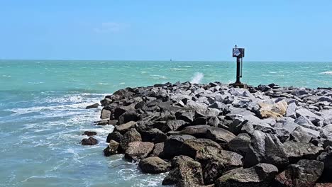 Static-view-of-waves-crashing-on-rock-wall-near-beach-post-in-cocoa-beach,-Florida