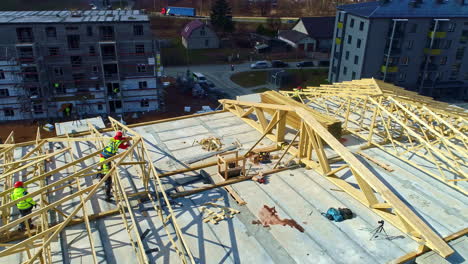 Workers-with-security-fluorescent-clothes-build-a-wooden-structure,-Highway-city-scene,-aerial-drone-shot