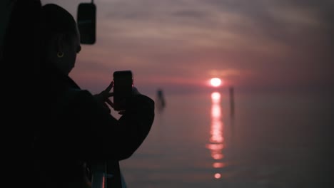 Silhouette-capturing-on-a-phone-serene-Burano-sunset,-Venice