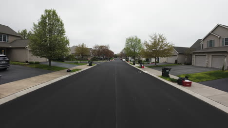 Dynamic-FPV-flight-over-street-in-american-residential-neighborhood-during-cloudy-day-in-spring