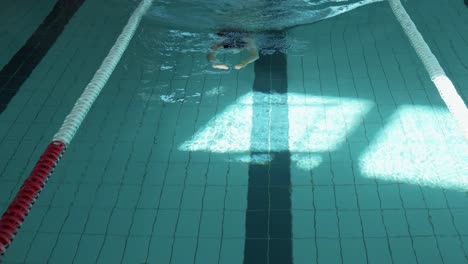 Eine-Ruhige-Aufnahme-Einer-Weiblichen-Figur,-Die-Gemütlich-In-Einem-Umzäunten-Poolbereich-Schwimmt,-Während-Natürliches-Licht-Auf-Das-Wasser-Fällt