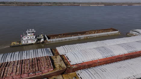 Aerial-footage-focused-on-a-tug-boat-that-is-pushing-against-a-barge-full-of-scrap-metal-in-Baton-Rouge,-Louisiana