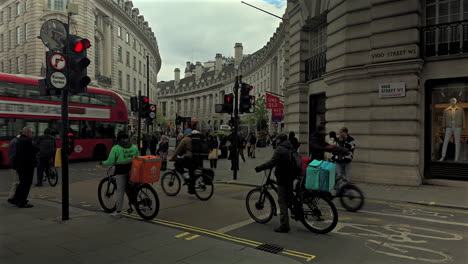 Cycle-couriers-wait-at-traffic-lights-on-Vigo-Street-and-Regents-Street,-London,-Day