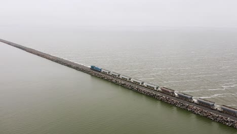 Largo-Tren-De-Carga-Industrial-En-Vía-Recta-Por-Mar-En-Argentina,-Panorámica-Aérea