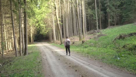 Woman-in-her-25s-is-traveling-alone-with-a-backpack-through-the-forest-in-spring