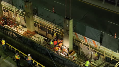 Telephoto-drone-shot-workers-installing-steel-at-the-East-river,-night-in-NY