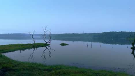 Morgens-Ruhiger-See,-Vor-Sonnenaufgang-Spiegelt-Sich-Der-See-In-Den-Atmosphärischen-Effekten-Des-Himmels-Und-Ist-Von-Nebligen-Nebeln-Umgeben