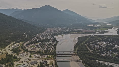 Revelstoke-BC-Canada-Aerial-v4-drone-flyover-above-Columbia-river-capturing-scenic-landscape-of-riverside-residential-area,-town-center-and-forested-mountains---Shot-with-Mavic-3-Pro-Cine---July-2023