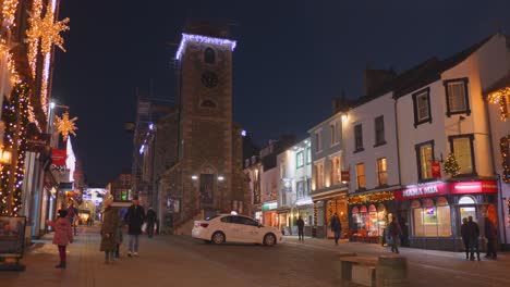 Toma-Panorámica-De-Los-Lugareños-Caminando-Por-El-Centro-De-La-Torre-En-Keswick,-Lake-District,-Cumbria,-Inglaterra-Durante-La-Noche.