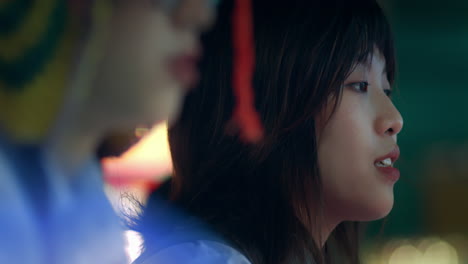 Closeup-of-two-asian-girls-focusing-playing-carnival-game-at-night