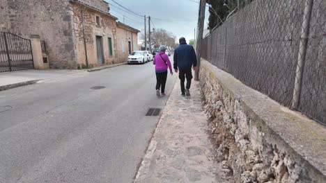 People-walking-down-the-paved-sidewalk-in-Algaida,-Mallorca,-Spain