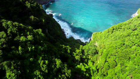 Summits-of-lush-greenery,-water-of-turquoise,-incoming-white-tide-waves