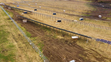 Aerial-view-of-solar-panel-farm-on-rural-field-during-Installation-process