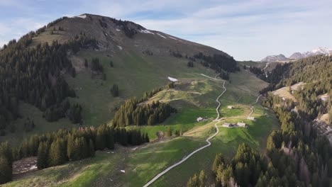 Pintoresca-Toma-Aérea-Del-Valle-En-Amden-Arvenbuel,-Suiza-Con-Caminos-Que-Suben-A-Las-Montañas-Con-Algunas-Casas-Y-Graneros-A-Lo-Largo-Del-Camino