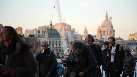 Pedestrians-stroll-past-as-sunlight-illuminates-London's-skyline,-including-St