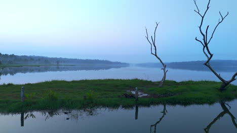 Morgens-Ruhiger-See,-Vor-Sonnenaufgang-Spiegelt-Sich-Der-See-In-Den-Atmosphärischen-Effekten-Des-Himmels-Und-Ist-Von-Nebligen-Nebeln-Umgeben