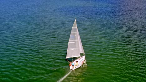 Draufsicht-Auf-Ein-Segelboot,-Das-Auf-Einem-Ruhigen-Grünen-See-Kreuzt