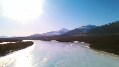 Gefrorener-Fluss-In-Jakutien,-Blaues-Eis,-Blauer-Himmel,-Grauer-Wald,-Strahlende-Sonne