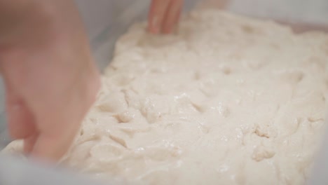 Kneading-dough-in-a-bowl-with-fingertips,-close-up-view