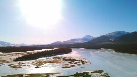 Volando-Sobre-Un-Río-Helado-Y-Un-Bosque-Gris-En-La-Soleada-Yakutia-A-Vista-De-Pájaro-4k