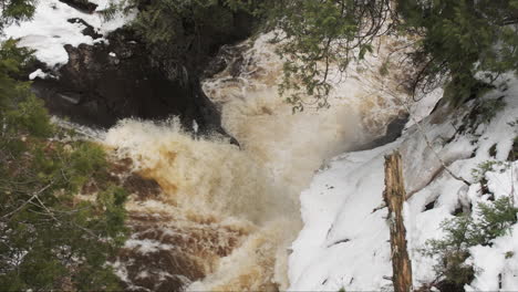 Looking-down-through-pine-trees-at-a-cascading-winter-waterfall