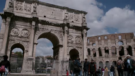 Tourists-and-pilgrims-near-Arch-of-Constantine,-Roman-Colosseum-in-background