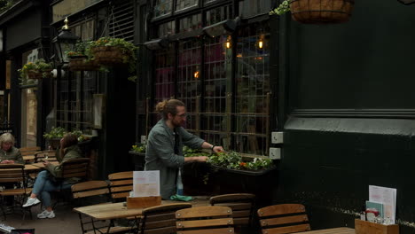 Staff-memeber-arranging-flowers,-Shakespeare's-Head-pub,-Carnaby-Street,-London,-Medium-Shot,-Day,-Exterior